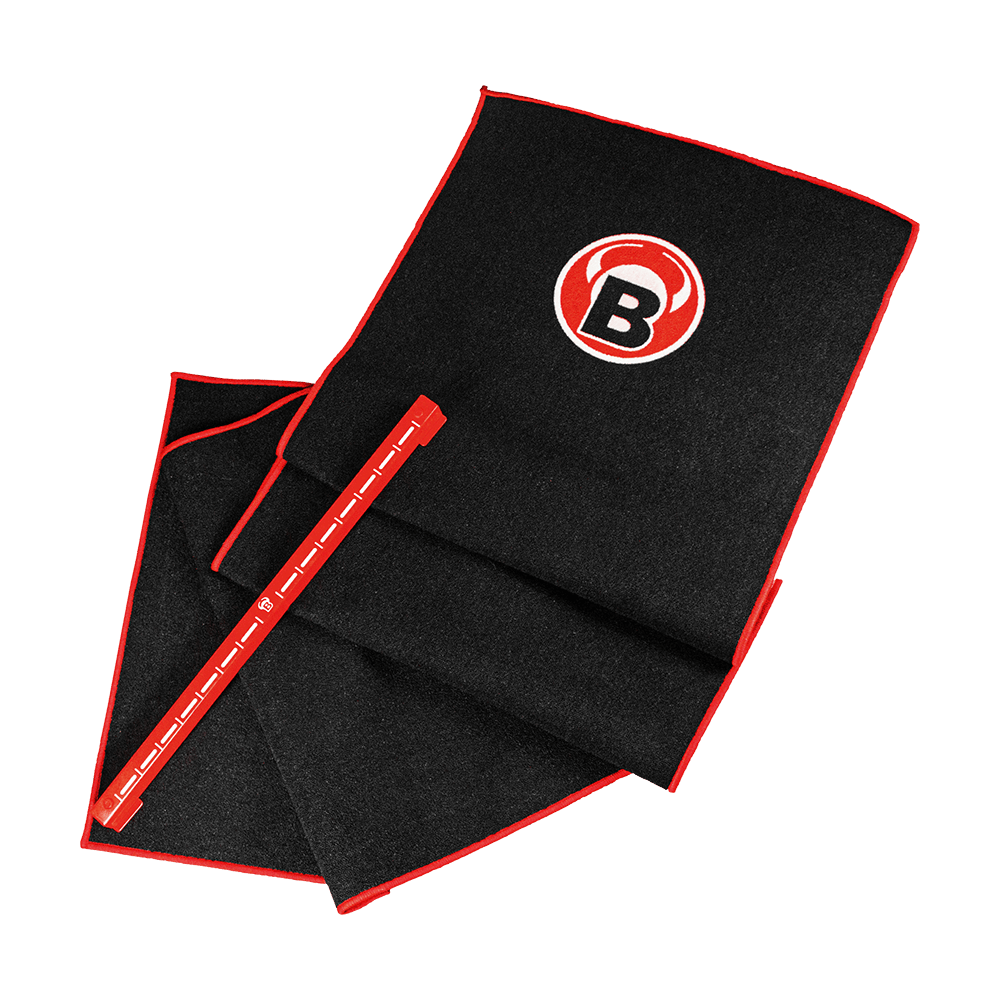 Das Bild zeigt das Bulls Oky System Set, bestehend aus einem schwarzen Teppich mit rotem Rand und einem Metall Oche. Auf dem Teppich ist ein rundes Logo mit einem "B" zu sehen.