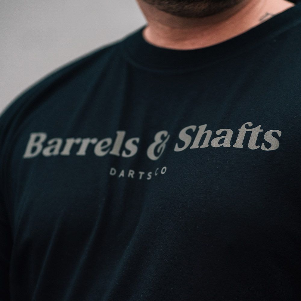 T-shirt „Barrels and Shafts” – czarny Das Bild zeigt ein schwarzes T-Shirt mit der Aufschrift "Barrels & Shafts". Darunter steht in kleineren Buchstaben "DARTSCO".