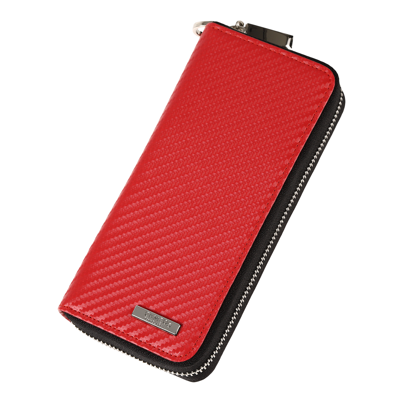 Das Bild zeigt ein rotes Etui mit einer strukturierten Oberfläche und einem Reißverschluss. An der unteren Ecke befindet sich ein kleines Metallschild mit einer Gravur.