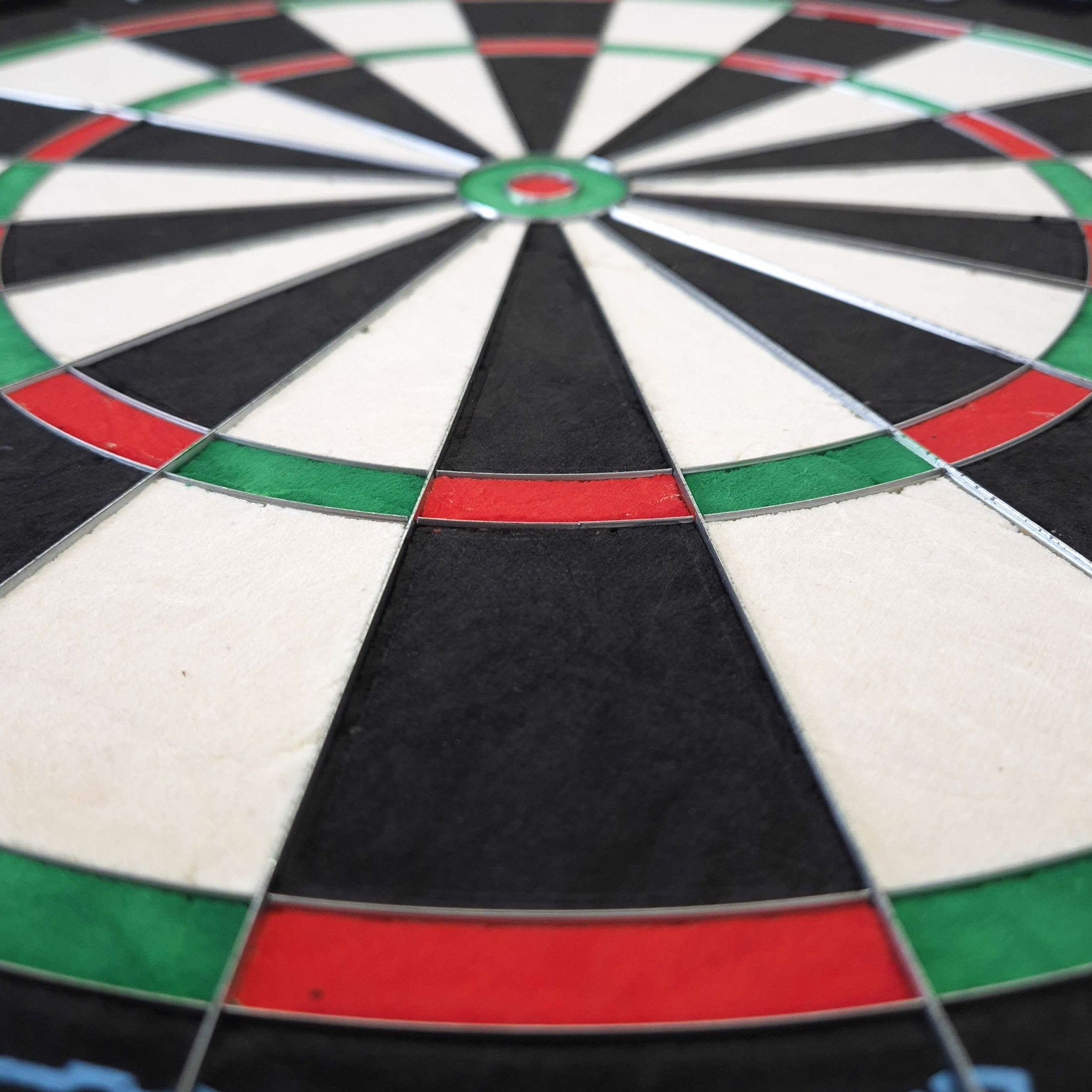 Tarcza do darta Mission Samurai Infinity ze stali Das Bild zeigt eine Nahaufnahme eines Steeldartboards mit klar erkennbaren Farbfeldern in Rot, Grün, Schwarz und Weiß. Es handelt sich um das Produkt "Mission Samurai Infinity Steeldartboard".