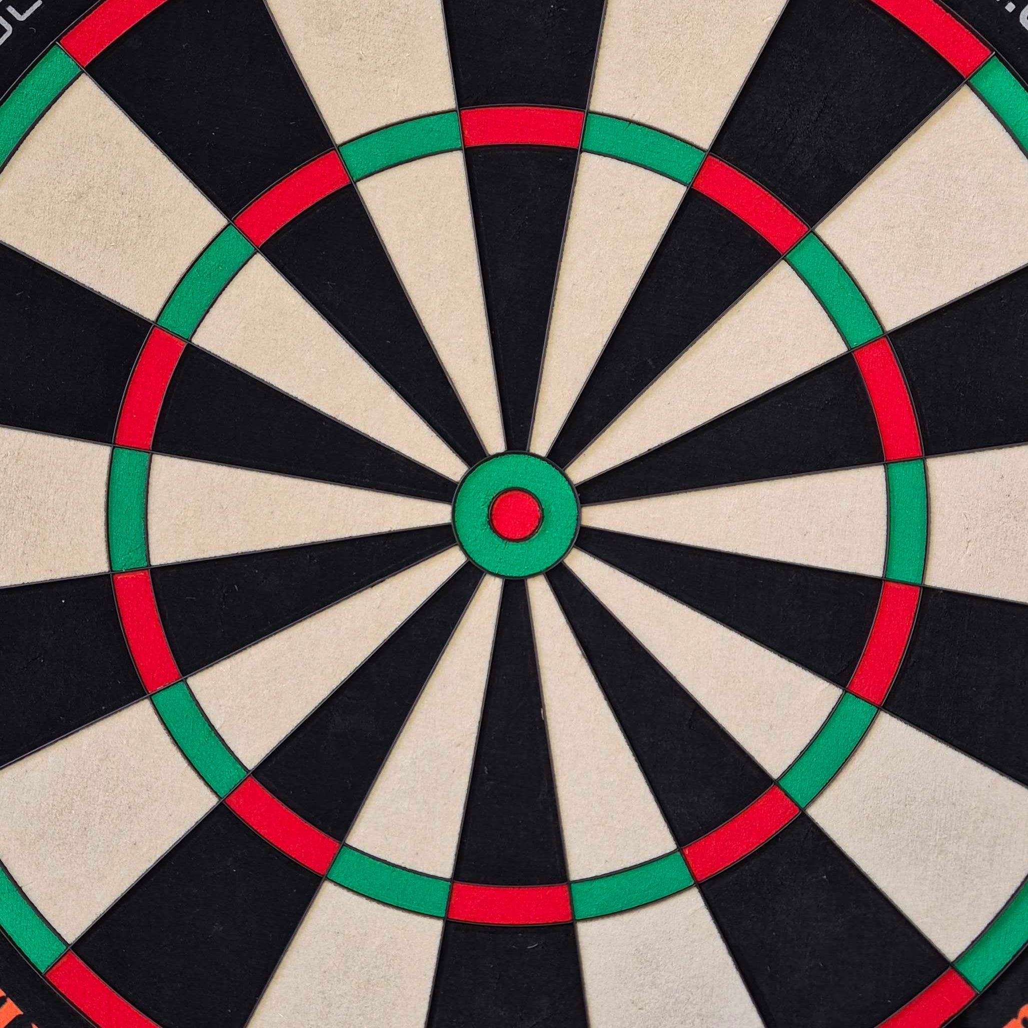Das Bild zeigt eine Nahaufnahme einer Dartscheibe mit klaren Farbfeldern in Schwarz, Weiß, Rot und Grün. Es handelt sich um das Produkt "Unicorn Eclipse Ultra 2.0 Steeldartboard".