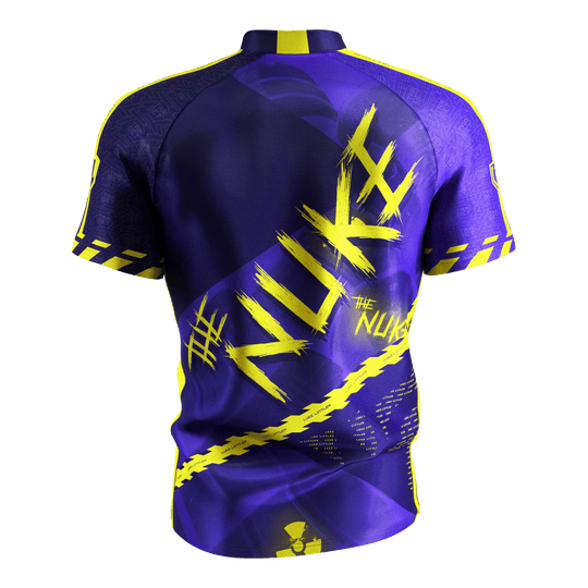 Das Bild zeigt das „Target Coolplay Luke Littler 2025 Dartshirt“ von hinten. Das Shirt ist überwiegend lila mit auffälligen gelben Designs und dem Schriftzug „NUKE“ auf dem Rücken.