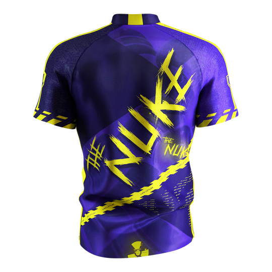 Koszulka do darta Target Coolplay Luke Littler 2025 Das Bild zeigt das „Target Coolplay Luke Littler 2025 Dartshirt“ von hinten. Das Shirt ist überwiegend lila mit auffälligen gelben Designs und dem Schriftzug „NUKE“ auf dem Rücken.