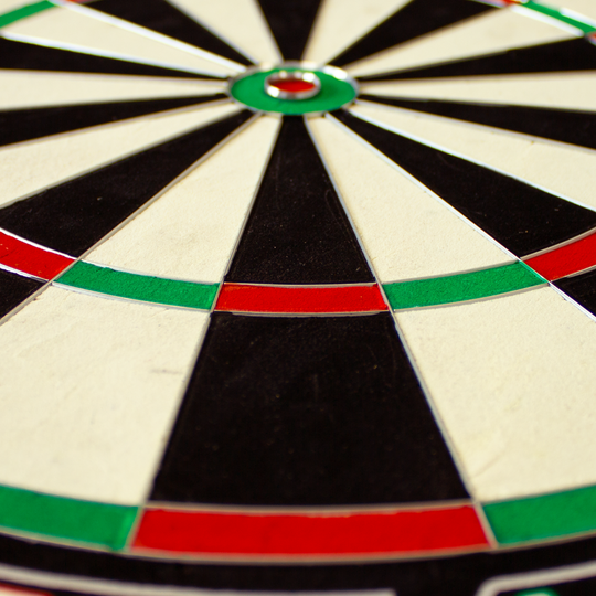Das Bild zeigt eine Nahaufnahme eines Steeldartboards der Marke "Unicorn Eclipse Ultra". Die Felder sind in Schwarz, Weiß, Rot und Grün unterteilt.