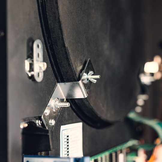 Das Bild zeigt einen Nahaufnahmebereich des Karella E-MASTER Dartautomaten ohne Münzeinwurf. Zu sehen sind Metallbefestigungen und elektronische Bauteile im Inneren des Geräts.