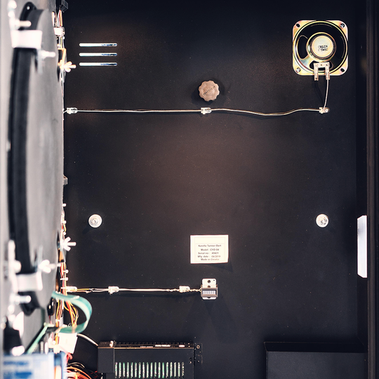 Das Bild zeigt das geöffnete Innere eines Karella E-MASTER Dartautomaten ohne Münzeinwurf. Verschiedene elektronische Komponenten und Kabel sind an der Innenwand sichtbar.