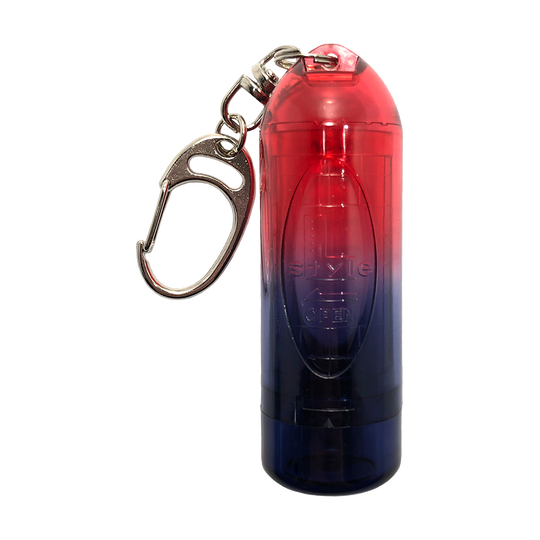 L9LIPSTOCK-RedEye_L-Style_Lipstock_Twin_Color_Red_Eye_Spitzencase_1 Das Bild zeigt das Produkt "L-Style N9 Lipstock Twin Color Spitzencase", ein zylinderförmiges Etui mit einem Farbverlauf von Rot zu Blau. Es besitzt einen Metallkarabiner zum einfachen Befestigen an Taschen oder Schlüsseln.