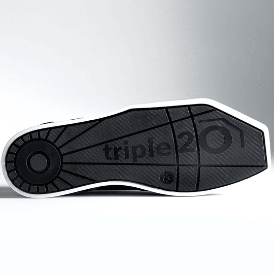 Auf dem Bild ist die Sohle eines Schuhs mit der Aufschrift „triple20“ zu sehen. Es handelt sich um den Triple20 Dartschuh aus Textil und Leder in Schwarz-Weiß.