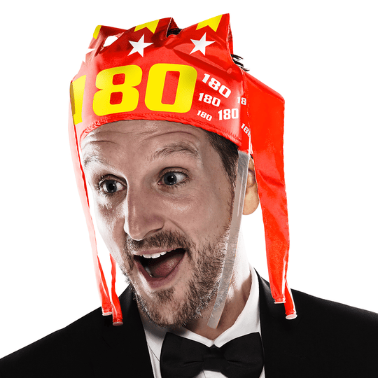 9026-McDart-180-er-Tr-tenkrone-2HGdV9DCXoxGIZ Ein Mann trägt eine auffällige, rote Partykrone mit der Aufschrift "180" und weißen Sternen. Er sieht überrascht und fröhlich aus.