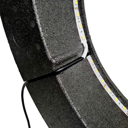 System oświetlenia przestrzennego Bulls NL Lumo Light Das Bild zeigt das „Bulls NL Lumo Light Surround Beleuchtungssystem“ mit LED-Leuchtstreifen auf einer schwarzen, strukturierten Oberfläche. Ein Kabel ist ebenfalls an das Beleuchtungssystem angeschlossen.