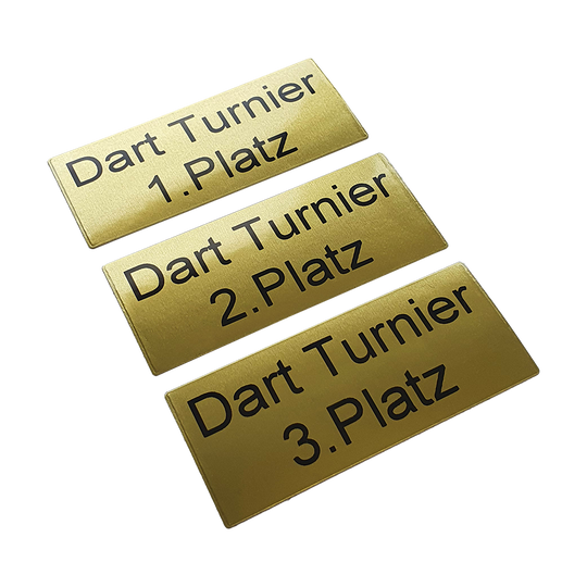 P-Schild_McDart_Pokalschild_mit_Wunschtext_2 Das Bild zeigt drei goldene Pokalschilder mit schwarzer Schrift. Auf den Schildern steht jeweils "Dart Turnier" und der Platz, zum Beispiel "1. Platz", "2. Platz" und "3. Platz".